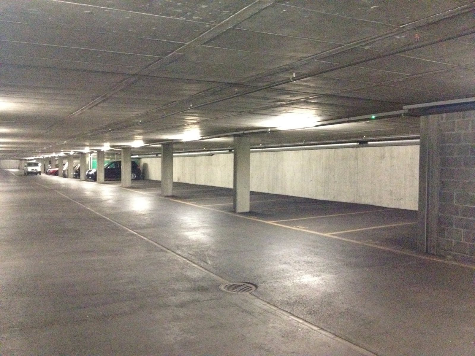 Blick durch die Tiefgarage Kornquader: lange Parkebene mit Betonstützen und parkierten Fahrzeugen